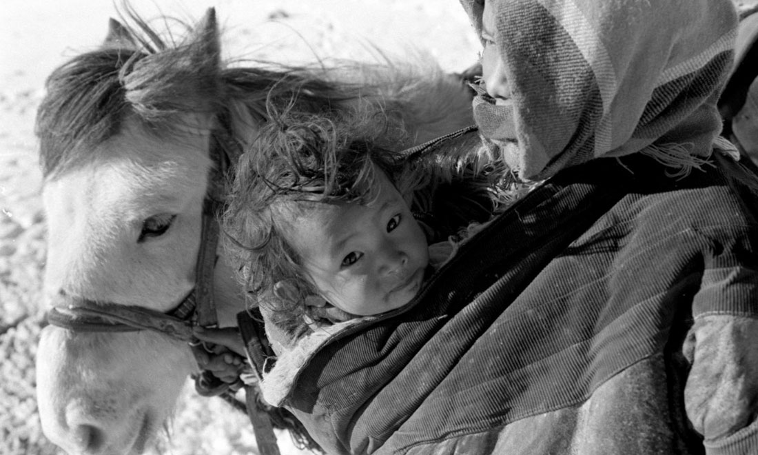 1990年3月，西藏當(dāng)雄縣納木湖鄉(xiāng)三村女牧民斯卓不畏嚴(yán)寒，懷抱幼子，準(zhǔn)備到遠(yuǎn)處放牧。新華社記者覺果攝