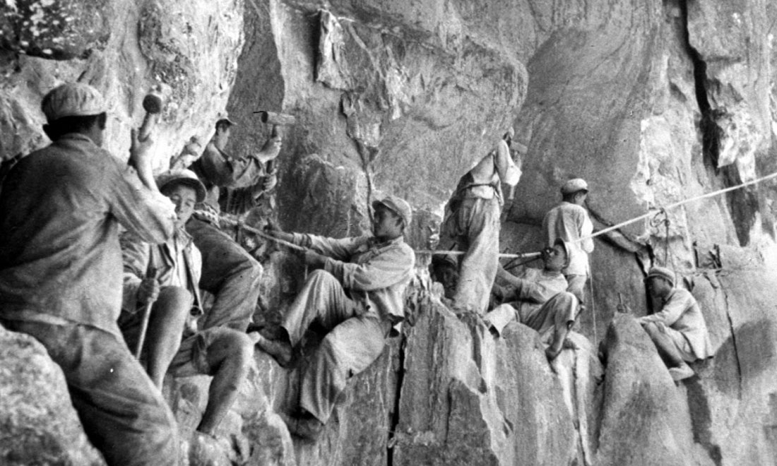 1954年，修筑康藏公路的解放軍戰(zhàn)士們在怒江兩岸的懸崖陡壁上辟山筑路。新華社稿 李萬春、張加里攝